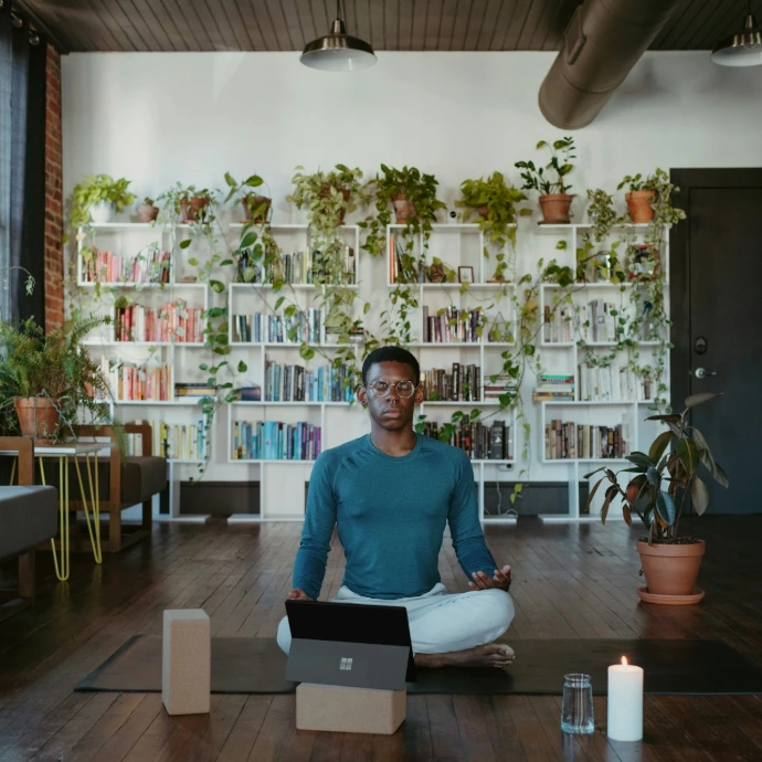 a man sitting on a yoga mat with a laptop in front of him